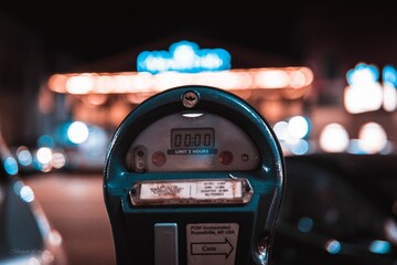 Shallow focus shot of a parking meter on the side of a street in a city
