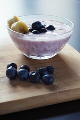 Vertical shot of yogurt in a glass bowl made of blueberries and bananas