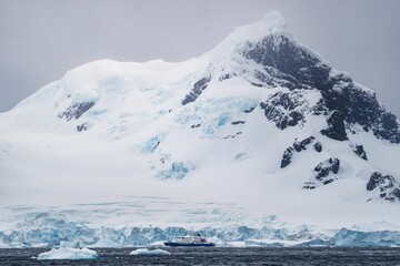 Snow-covered mountain and a ship in the glacier in Antarctica.