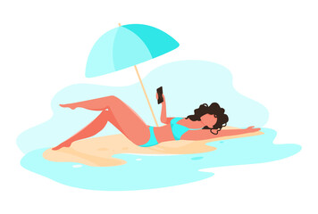 A girl by the sea lies on the sand under an umbrella. Summer paradise. Girl on the beach in a bikini. Summer vacation. A young brunette woman is lying on the beach and holding a mobile phone.