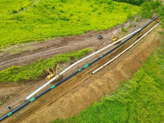 Aerial shot of pipeline construction surrounded by green grass in the field