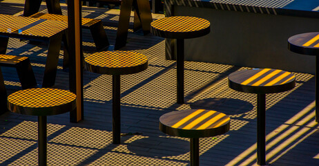tables and chairs in a cafe restaurant. empty tables and chairs on the terrace with sun glare and...