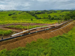 Aerial shot of pipeline construction surrounded by green grass in the field