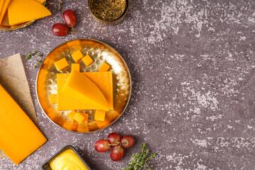 Composition with tasty cheddar cheese, grapes, sauce and herbs on grunge background