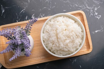 Bowl of rice with a small potted plant on a wooden board
