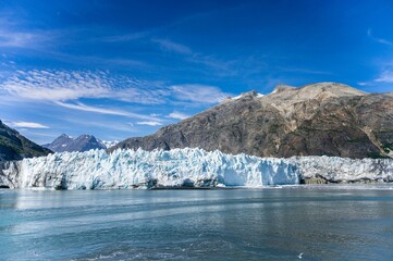 Big glacier in the frozen lake with big mountains in the background on a sunny day