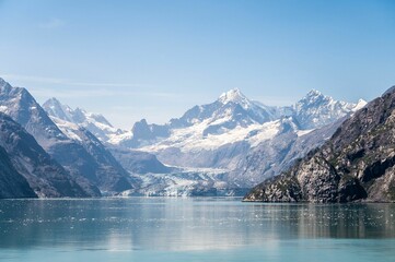 Calm blue sea with big snowy mountains in the background on a sunny day under the blue sky
