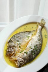 Vertical closeup shot of gilt-head bream fish (Sparus aurata) in a yellow sauce