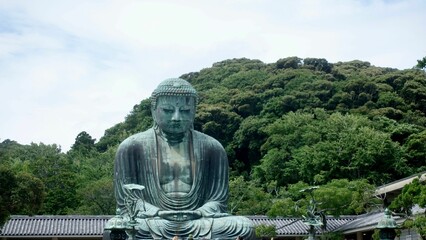 Statue of Buddha at the Kotoku-in temple in Kamakura Japan, with trees in the background