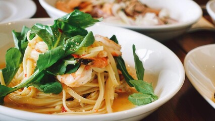 Closeup shot of pasta in a white plate with cheese and spinach on it