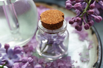Fototapeta na wymiar Bottles of cosmetic oil with beautiful lilac flowers and sea salt, closeup