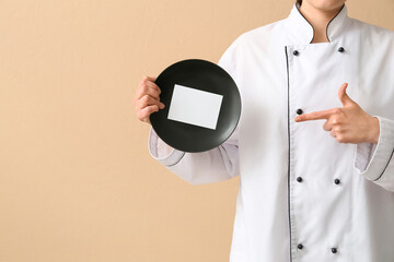 Female chef holding plate with blank card on beige background