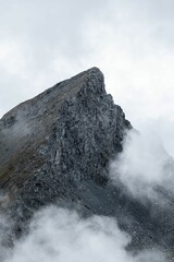 Vertical shot of a peak of a rocky mountain on a foggy day