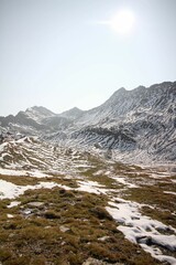 Vertical shot of high rocks covered in snow on a sunny day with a blue sky in the background