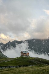 Vertical shot of a beautiful house with mountains and a cloudy sky in the background