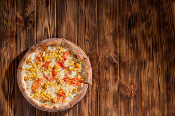 Pizza for children on a cream base with chicken fillet, tomatoes, corn and mozzarella cheese on wood background. Copy space.