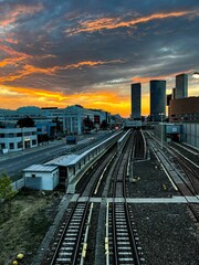 Fototapeta premium Vertical shot of a sunset over the railroad and buildings.