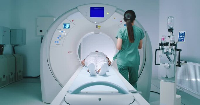 Shoot of equipped tomography chamber. Woman after magnetic resonance imaging. Patient is moving out of CT scanner bed. Nurse finishes MRI examining. Female gets out of MRI moving bed.