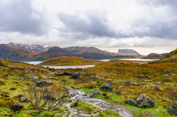 Norwegian mountains view from ground at the sea level. Cloudy weather add to the dramatic atmosphere. 