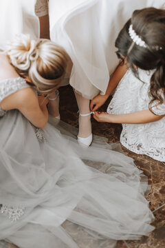 Girlfriends help the bride put on her wedding shoes. Beautiful female legs close-up