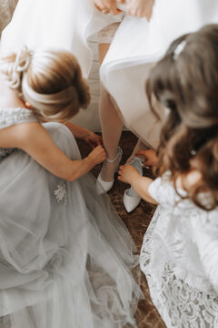 Girlfriends help the bride put on her wedding shoes. Beautiful female legs close-up