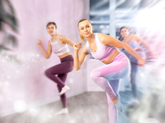 Obraz premium Positive women engaged in active dancing in the studio during a group workout