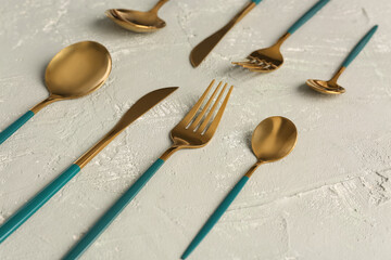 Golden set of cutlery with green handles on grey background