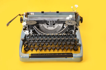 Vintage typewriter with white flowers on yellow background