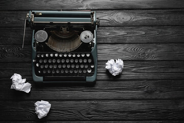 Vintage typewriter with crumpled paper on black wooden background