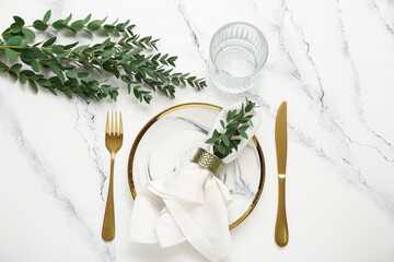 Plate with folded napkin and gold cutlery on grunge white background