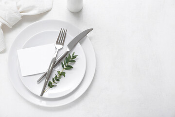Stylish table setting with blank card and plant branch on white background