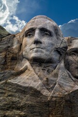 Vertical shot of Washington memorial at Mount Rushmore against blue cloudy sky