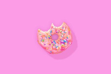 Top view of a bitten donut with sprinkles isolated on a pink background