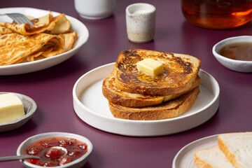 Morning meal - breakfast food. French toast with butter, pancakes, toast bread, jam, syrup, tea on...