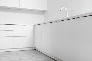 Interior of light kitchen with white drawers and sink
