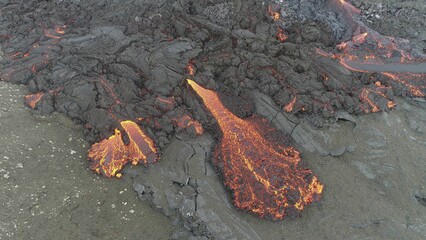 Volcanic eruption with glowing orange lava flow surrounded by a pool of bubbling magma