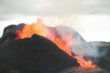 Volcanic eruption with glowing orange lava flow surrounded by a pool of bubbling magma