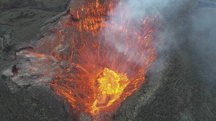 Volcanic eruption with glowing orange lava flow surrounded by a pool of bubbling magma