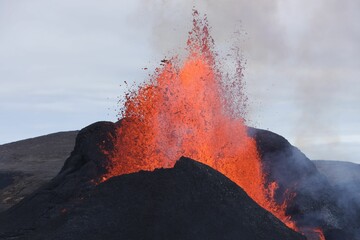 Volcanic eruption with glowing orange lava flow surrounded by a pool of bubbling magma