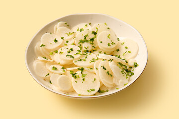 Bowl with slices of fresh daikon radish on yellow background