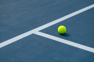 Landscape of a blue and green tennis court with a ball on it on a sunny day - obrazy, fototapety, plakaty