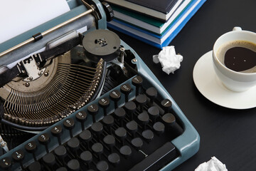 Vintage typewriter with cup of coffee and books on black background