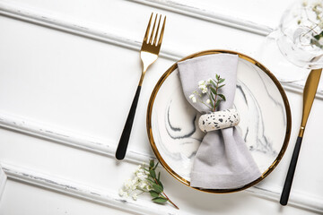 Plate with folded napkin, gold cutlery and glass on wooden white background - obrazy, fototapety, plakaty