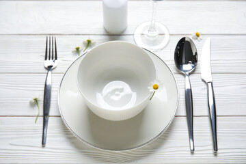 Stylish table setting and candle on white wooden background