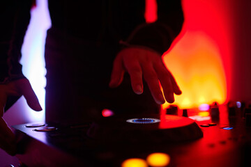 Hands of female Dj playing music on modern midi controller turntable. Digital device for mixing...