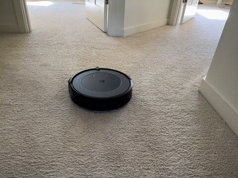 Seattle, WA USA - circa May 2023: Close up view of an iRobot Roomba on a light carpeted floor inside a family home.