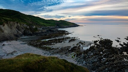 Scenic view of rocky beach and the sea under colorful cloudy sunset sky