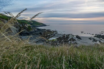 Shore covered with rocky mountains with a sea in the background during sunset