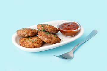 Cutlets with chopped parsley, ketchup and fork on blue background