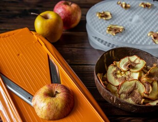 Apples being sliced by mandoline slicer to be dried